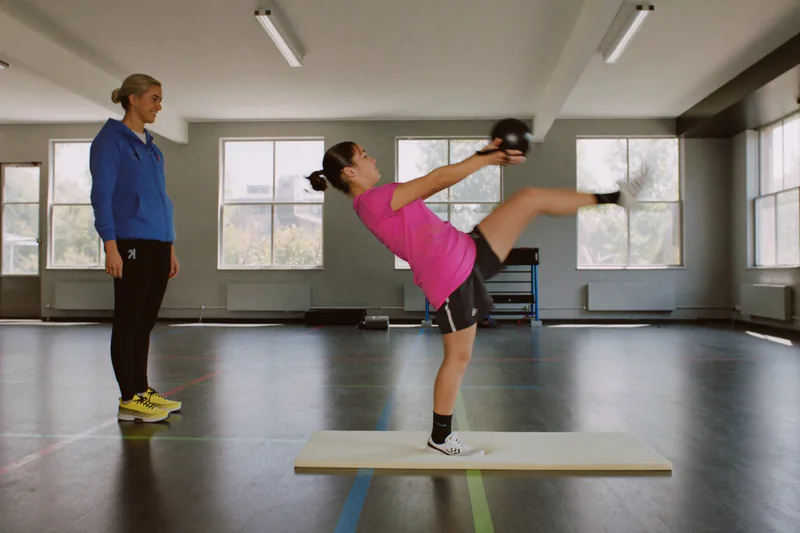 Supervised single-leg exercise while holding a ball.